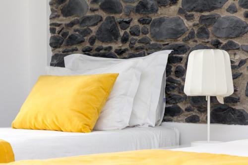 a bed with a yellow pillow and a stone wall at Apartamentos Funchal by Petit Hotels in Funchal