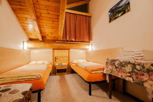mały pokój z 2 łóżkami i stołem w obiekcie Giacomino Apartment w Livigno