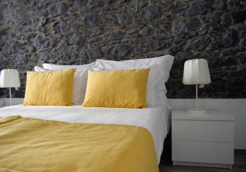 a bedroom with a bed with yellow pillows and a stone wall at Apartamentos Funchal by Petit Hotels in Funchal