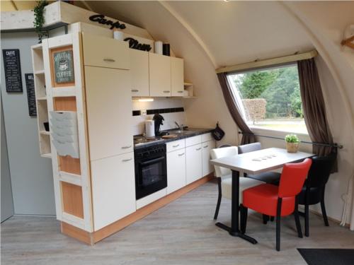 a kitchen and dining room with a table and a window at Iglo Bungalow 36 in Chaam
