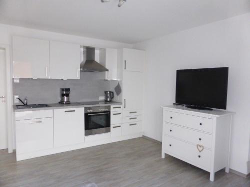 a kitchen with white cabinets and a flat screen tv at Ferienwohnung Selina-Sophie in Sehringen