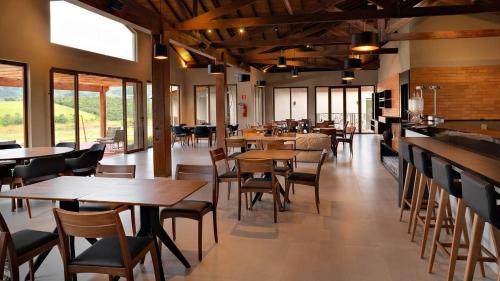 a restaurant with wooden tables and chairs and windows at Pousada Terramare in Guapé