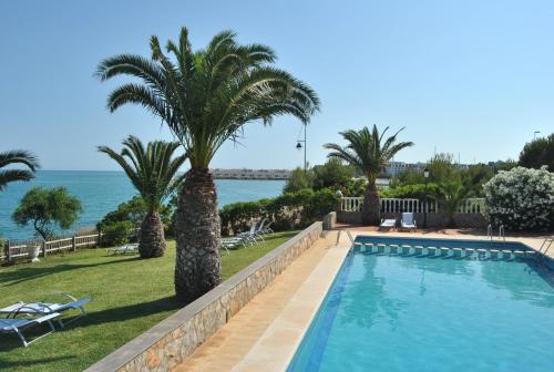 a swimming pool with palm trees and the ocean at Hotel Sancho III in Alcossebre