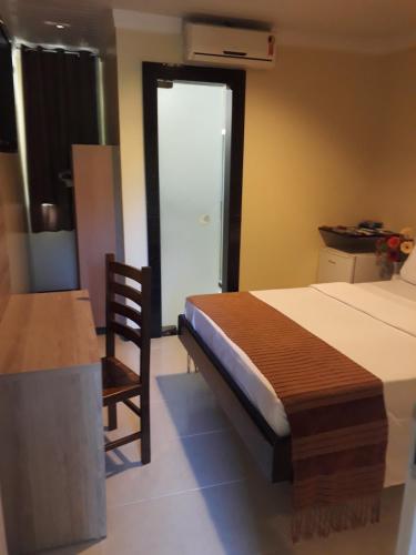 a bedroom with a bed and a chair and a table at Hotel Sempre Bahia in Salvador
