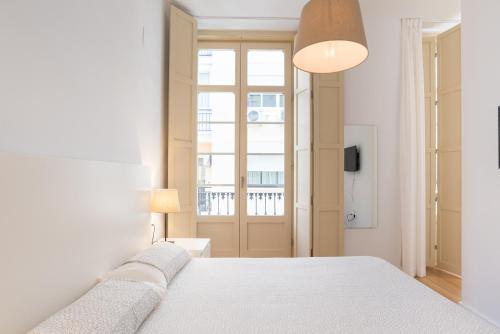 ein Schlafzimmer mit einem weißen Bett und einem Fenster in der Unterkunft LU&CIA SOHO free breakfast! in Málaga