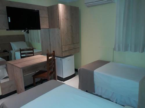 a bedroom with two beds and a desk and a television at Hotel Sempre Bahia in Salvador