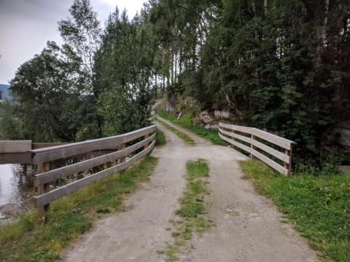 a dirt road next to a fence next to a river at Ivaregga Vinterstua in Tolga