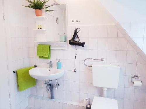 La salle de bains blanche est pourvue d'un lavabo et de toilettes. dans l'établissement 25mn to HH-2BR Kitchen&Netflix, à Elmshorn