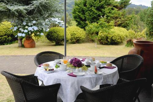 a table with a white table cloth and flowers on it at Quinta Da Cova Do Milho in Santo António da Serra