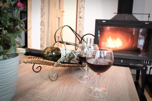 two glasses of wine on a table in front of a fireplace at Domki pod Bukowym lasem in Wańkowa