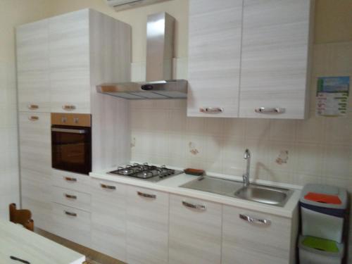 cocina con armarios blancos, fregadero y fogones en Casa di Jerry Castellabate 2, en Santa Maria di Castellabate