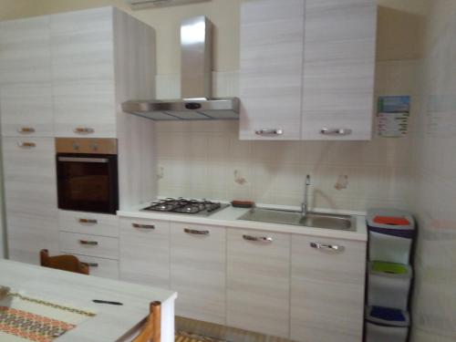 cocina con armarios blancos, fregadero y fogones en Casa di Jerry Castellabate 2 en Santa Maria di Castellabate