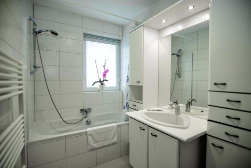uma casa de banho branca com um lavatório, uma banheira e um espelho. em S-HOF Appartment em Sonnenbühl