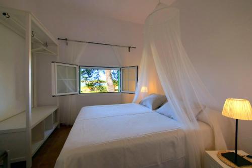 a bedroom with a bed with a mosquito net at Bungalows del Lago - Astbury Formentera in La Savina