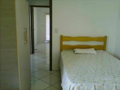 1 dormitorio con 1 cama y puerta que conduce a un pasillo en Aluguel de Verão, en Torres
