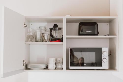 een witte kast met een magnetron en wat servies bij Casa Nuestra in Cordoba