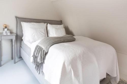 a white bed with white sheets and pillows at Maison de l'Epée in Emmeloord