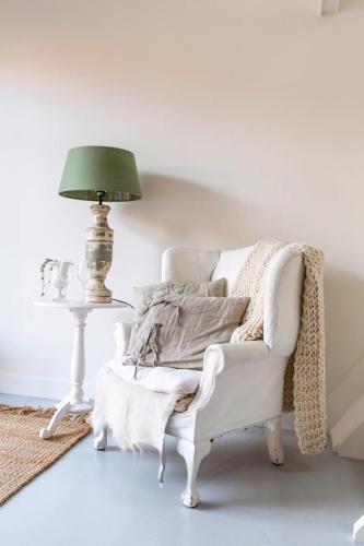 a living room with a white chair and a lamp at Maison de l'Epée in Emmeloord