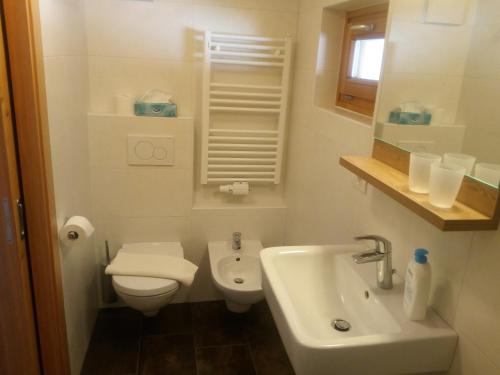 a white bathroom with a toilet and a sink at Chalet Rasteck in Campo Tures