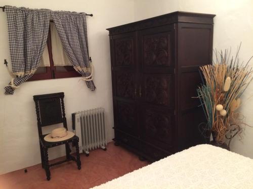 a bedroom with a large wooden cabinet and a chair at Ninho das Perdizes - Monte Novo in Cercal