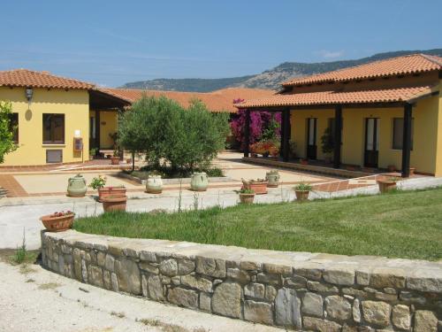 a house with a stone wall in front of a yard at Hotel Su Nuraxi in Barùmini