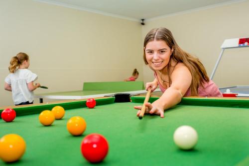 a girl playing pool with a cue on a pool table at NRMA Ballarat Holiday Park in Ballarat