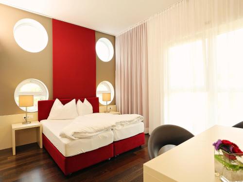 a bedroom with a bed with a red wall at Hotel Royal X in Seeboden