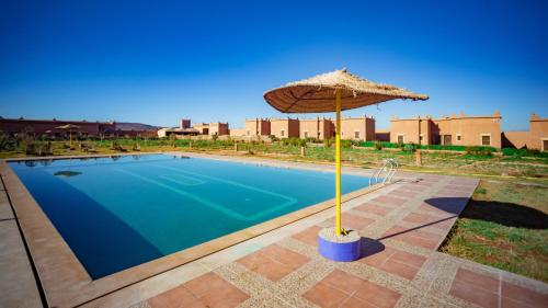 an umbrella next to a swimming pool with at Ecolodge l'île de Ouarzazate in Ouarzazate