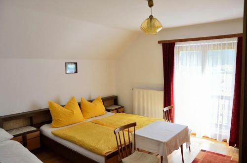 a bedroom with a bed with yellow sheets and a window at Gästehaus Santer in Rothenthurn