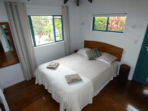 um quarto com uma cama branca e 2 janelas em Aroa Kainga Bungalows and Apartment em Rarotonga