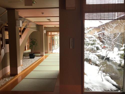 a door leading to a hallway with snow on the ground at Keiryuso Siorie in Matsumoto