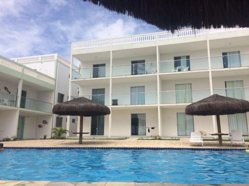 a hotel with a swimming pool and two umbrellas at Apartamento em Jacumã PB in Jacumã