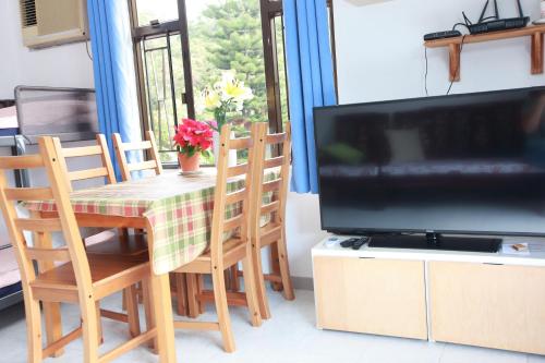 ein Esszimmer mit einem Tisch und einem TV in der Unterkunft Lantau Lodge in Hongkong