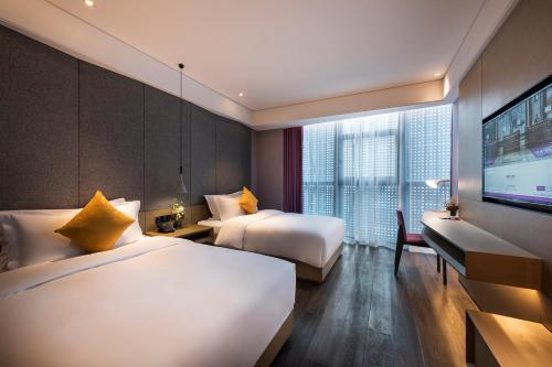 a hotel room with two beds and a flat screen tv at Mercure Suzhou Downtown in Suzhou
