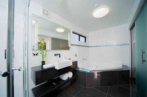 Baño blanco con lavabo y bañera en Best Western Ellerslie International Hotel, en Auckland