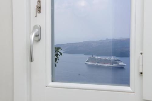 a cruise ship in the water through a window at Panorama Suites in Fira