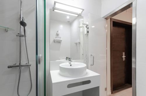 a white bathroom with a sink and a shower at Hotel INN Rossio in Lisbon