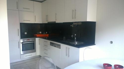 a kitchen with white cabinets and a sink and a table at Marginal Luminous Beach Apartment in Vila do Conde