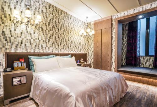 a bedroom with a large white bed and a window at Shu Xin Motel in Nantou City