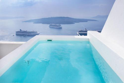 a swimming pool with a view of the ocean and ships at Panorama Suites in Fira