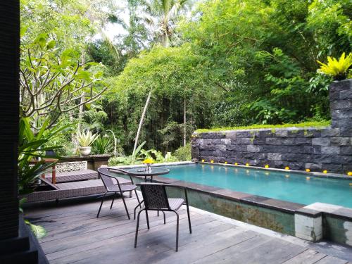 Ubud Harmony Private Villa and Pool في أوبود: فناء مع طاولة وكراسي بجوار حمام سباحة