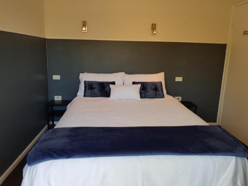 een groot bed met blauwe en witte lakens en kussens bij Waterfront Location - 2 Bed Apartment in Corlette, Port Stephens - Sleeps 4 in Corlette