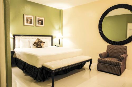 1 dormitorio con cama, silla y espejo en Dreamwave Hotel Ilagan, en Ilagan