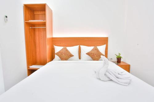 a bedroom with a bed with white sheets and pillows at Sandy's Homestay in Banyuwangi
