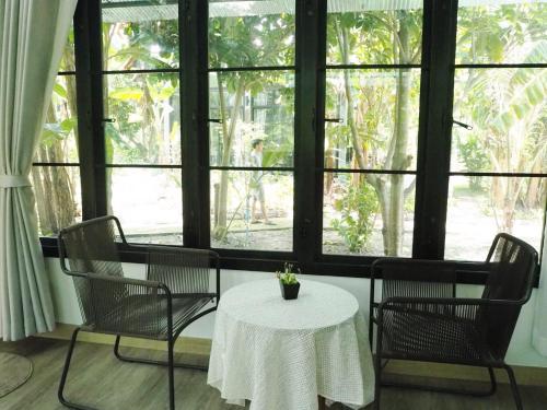 a table and chairs with a white table and a window at Bann Rai Klai Weang Homestay in Ban Muang Chum