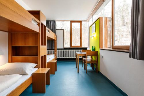 a bedroom with a bunk bed and a desk and a table at Jugendherberge Possenhofen in Pöcking