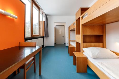 a room with a bed and a desk and bunk beds at Jugendherberge Possenhofen in Pöcking