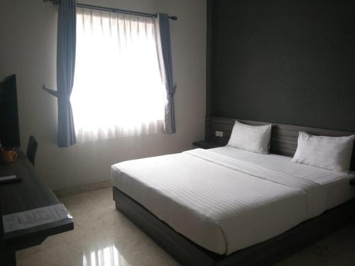 una camera da letto con un grande letto bianco con una finestra di Tulip Guest House a Bandung