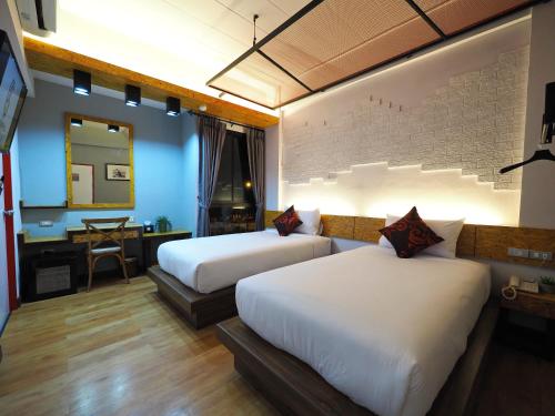 um quarto com 2 camas e uma secretária com um espelho. em Ps Sriphu Hotel em Hat Yai