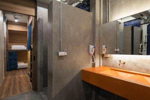 un bagno con lavandino, doccia e specchio di Natee Hostel a Bangkok